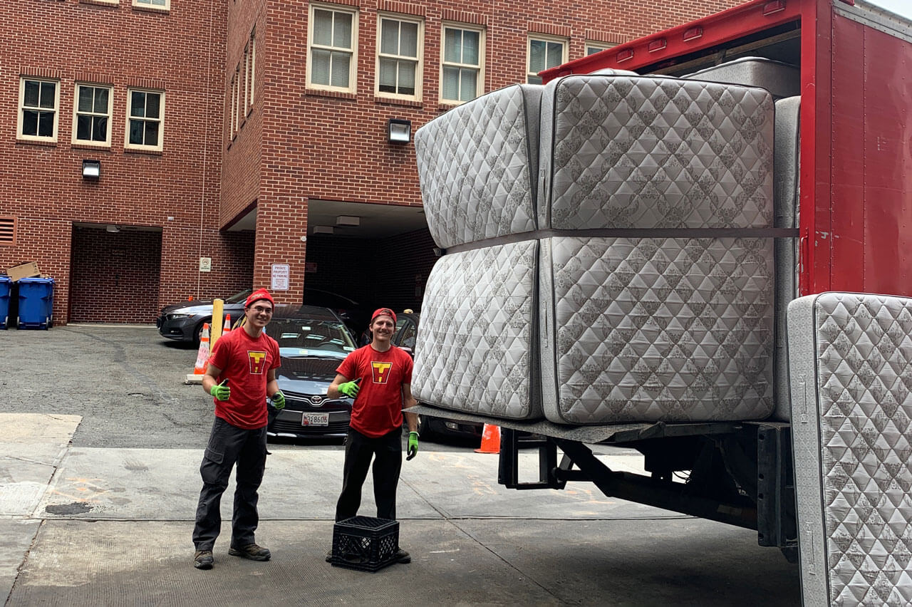 Two TurboHaul employees load mattresses into their junk hauling trucks.