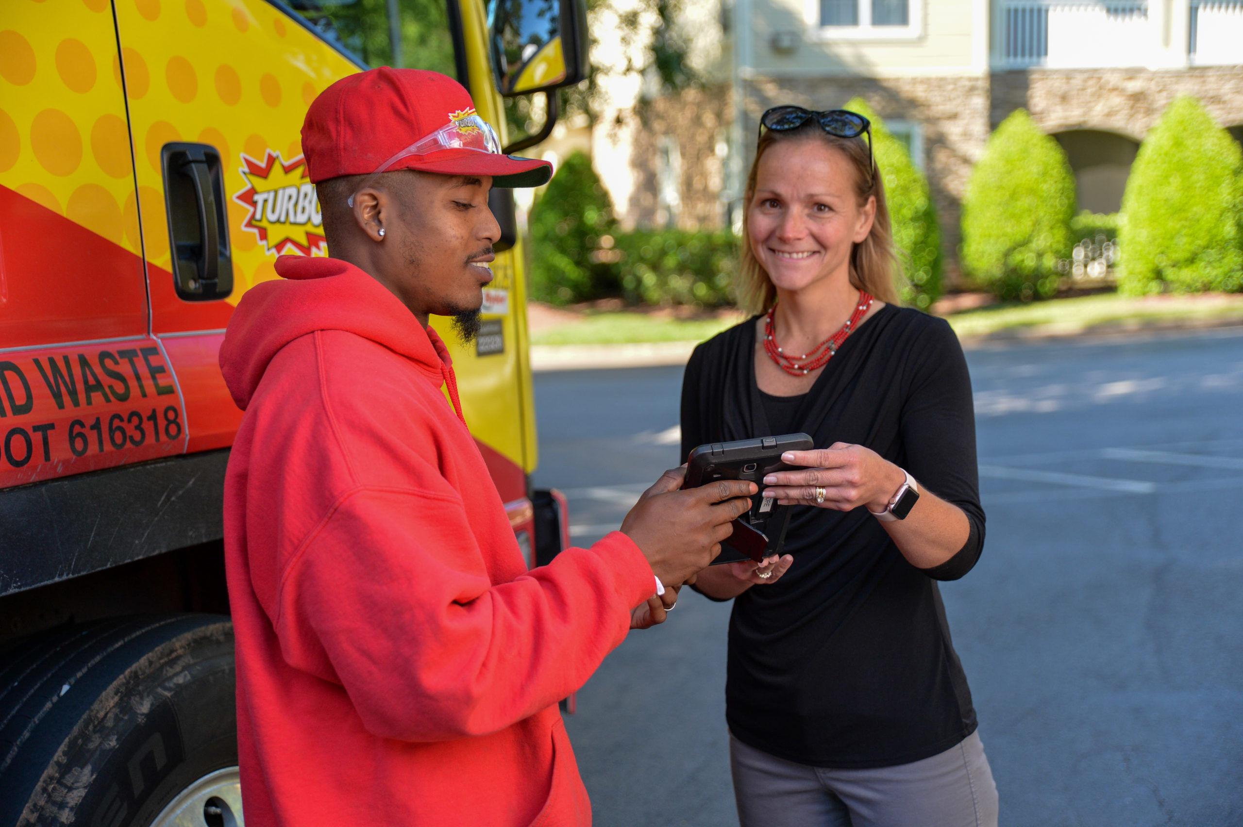 Two junk removal specialists hold an iPad and smile in Camp Springs, Maryland