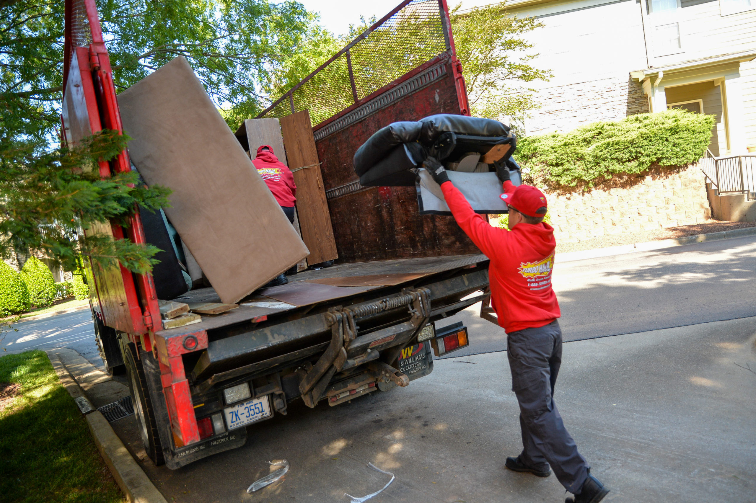 A Cooksville, MD junk removal specialist throws part of an old seat cushion into a truck